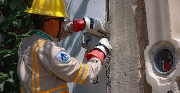 Trabajadores instalan medidores de energía eléctrica en una colonia de Cancún.