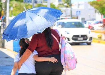 Persona se protege del intenso calor mientras camina bajo el sol en Quintana Roo durante la temporada de altas temperaturas.