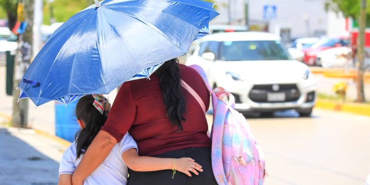 Persona se protege del intenso calor mientras camina bajo el sol en Quintana Roo durante la temporada de altas temperaturas.